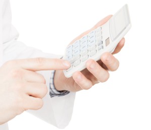 Medical doctor with a calculator in his left hand calculating costs and revenues in physician practice and hospital fees